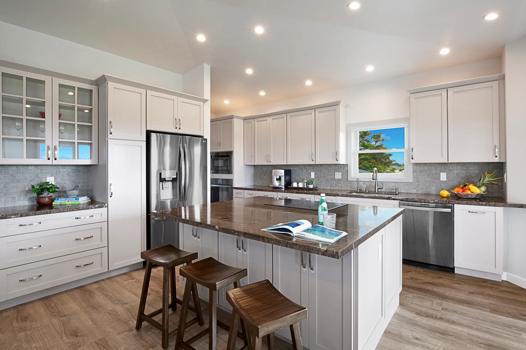 A bright kitchen with a central island, dark countertop, and stainless steel appliances.