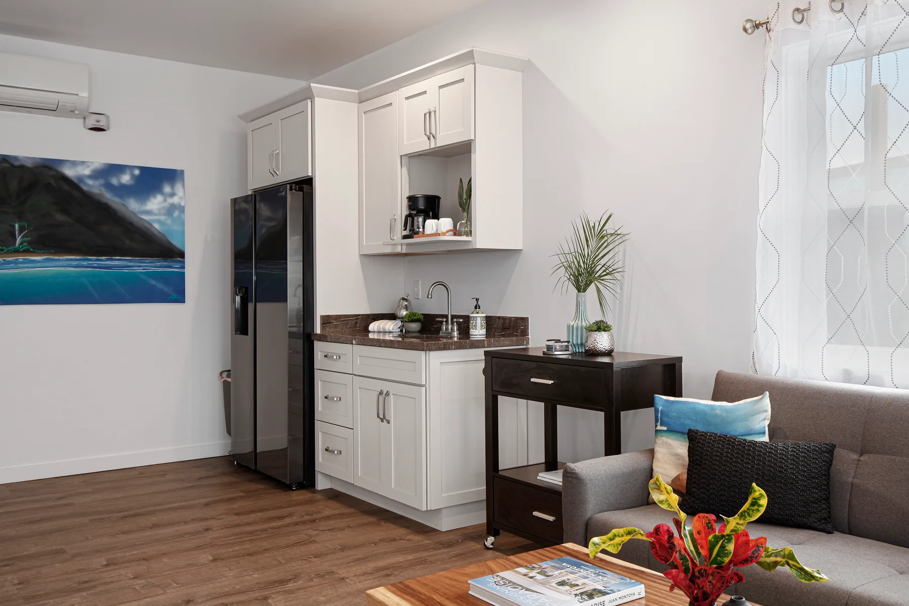 A compact kitchen and seating area with white cabinets and a gray sofa.