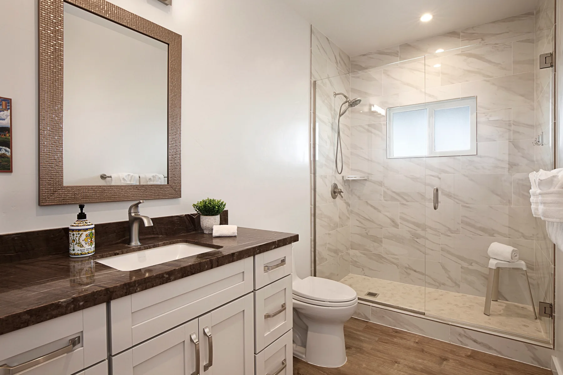 A bathroom vanity and sink sit beside a glass-enclosed shower.