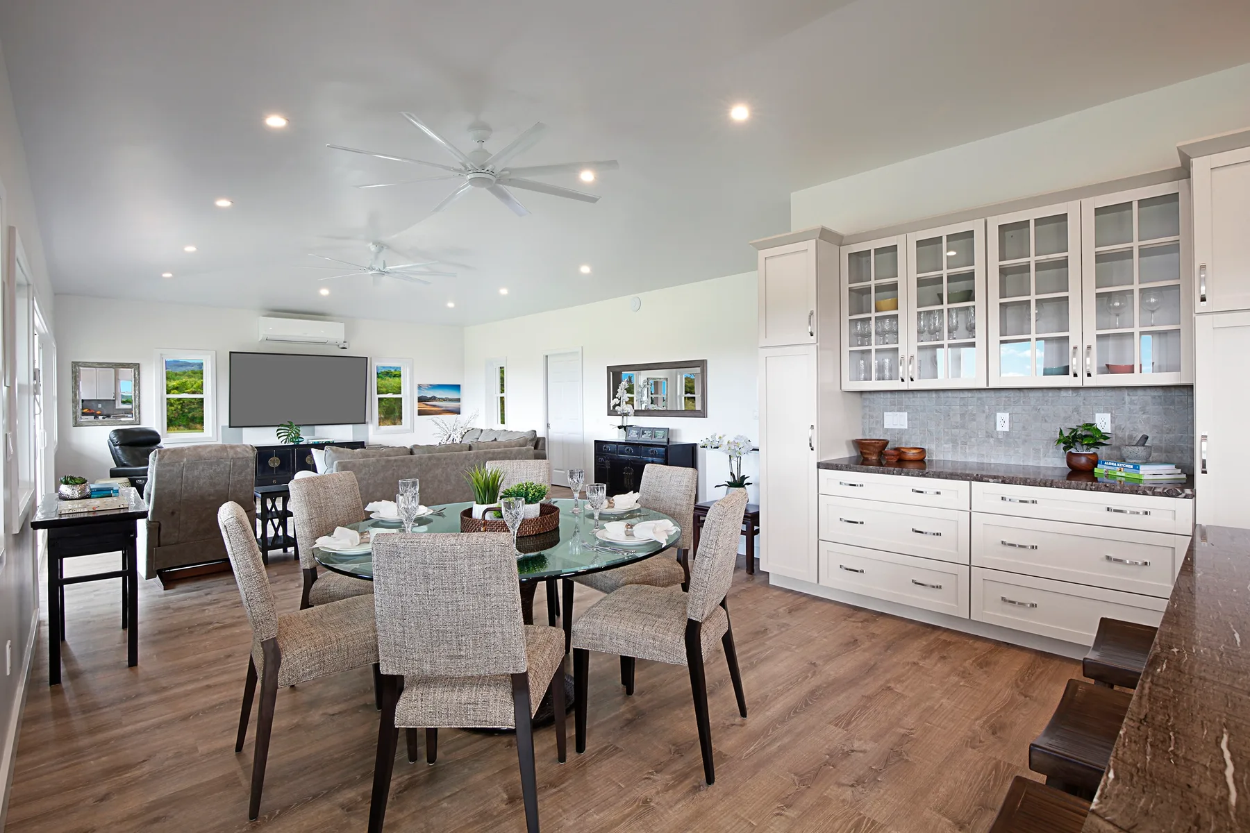 An open dining and living area with a glass dining table and kitchen cabinetry.