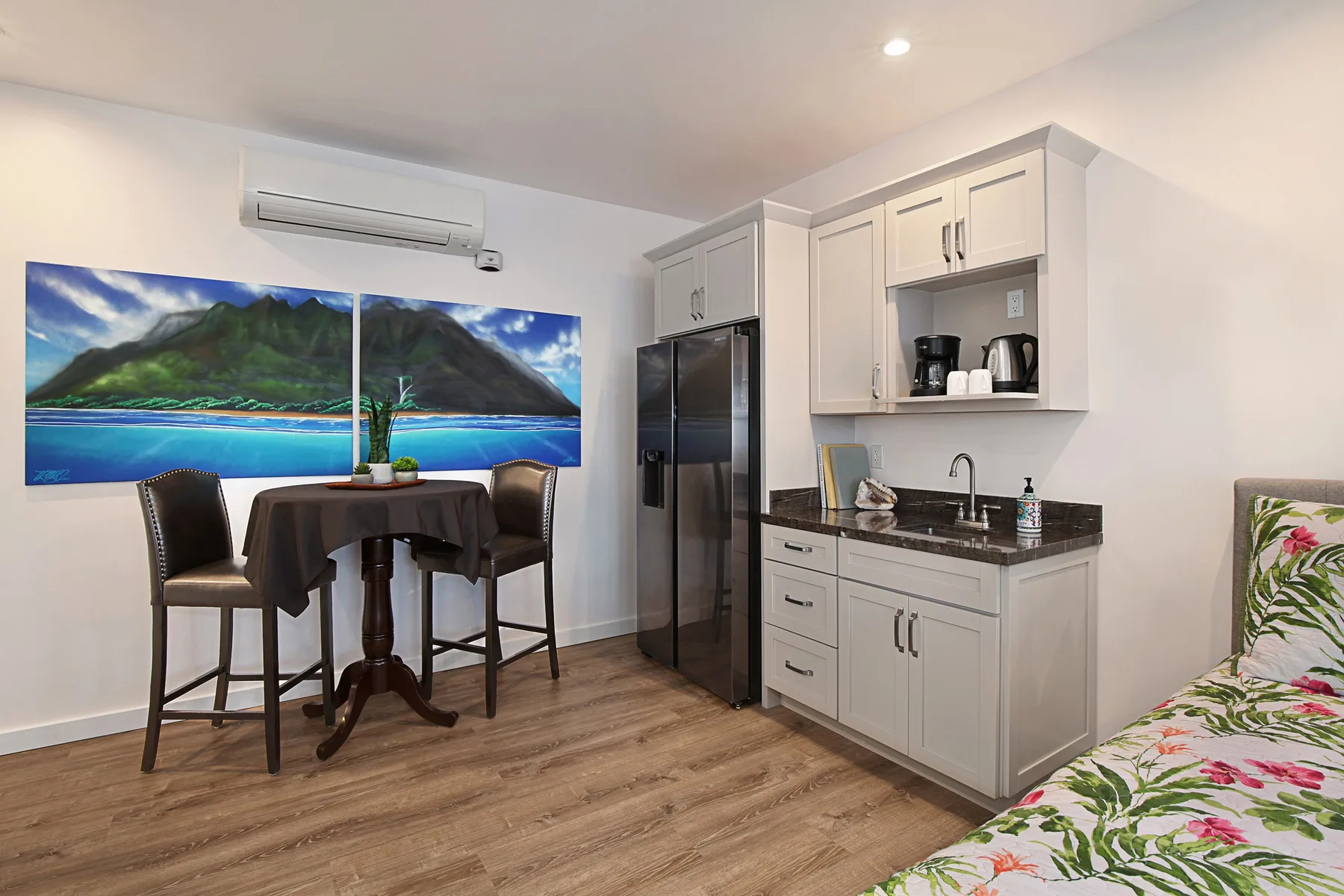 A compact kitchenette and dining area with a small table and wall art.