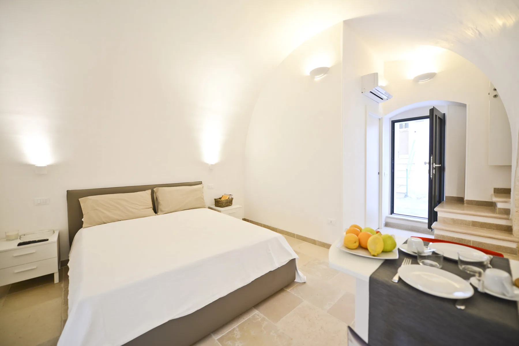 Un dormitorio luminoso con una cama doble y una pequeña zona de comedor.