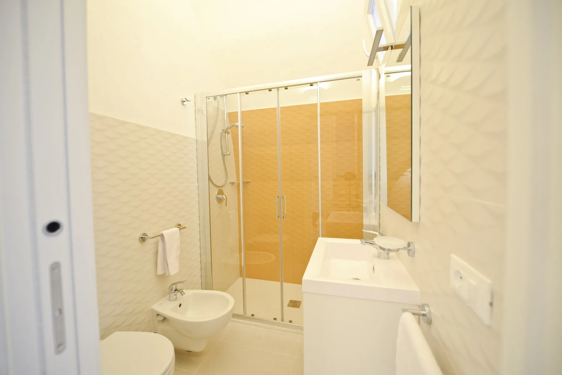 Un baño luminoso con ducha, lavabo y bidé.