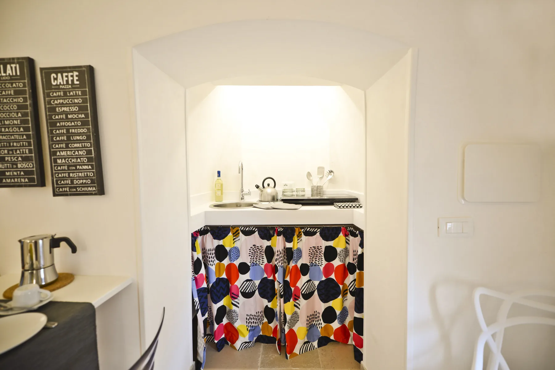 Una pequeña cocina con una cortina de estampado colorido debajo de la encimera.