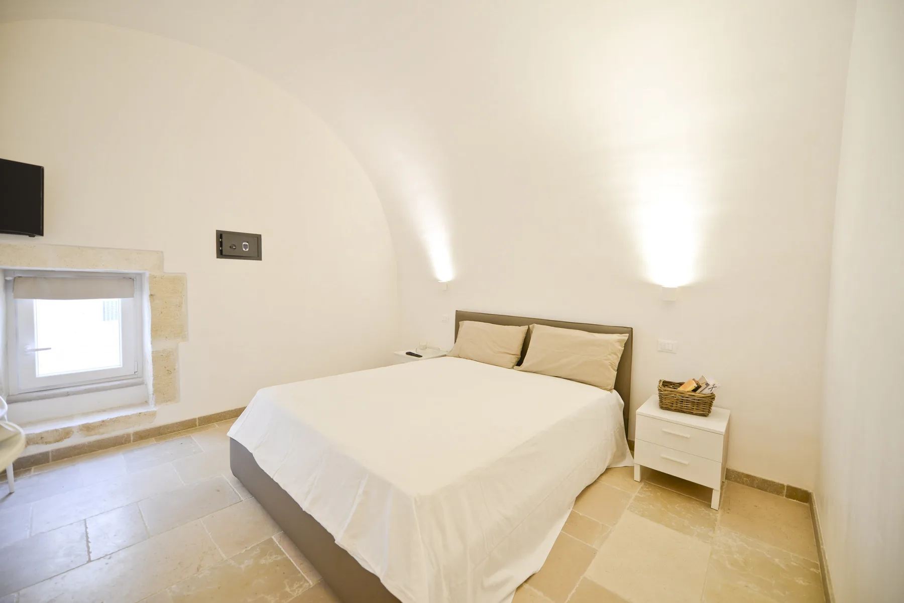 Un dormitorio con una cama tendida y una mesita de noche.
