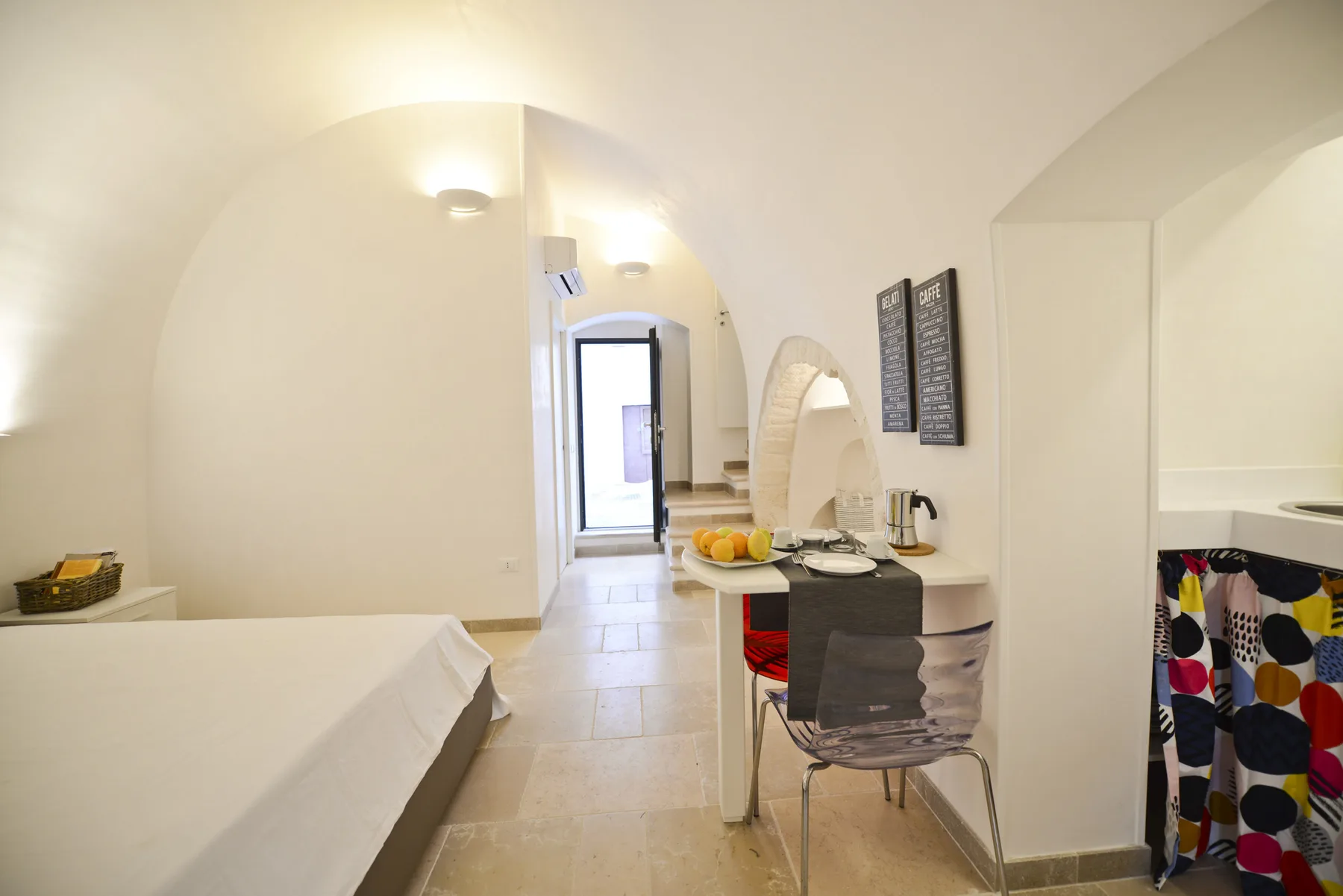 Una habitación luminosa con una cama, una mesa pequeña y una puerta.