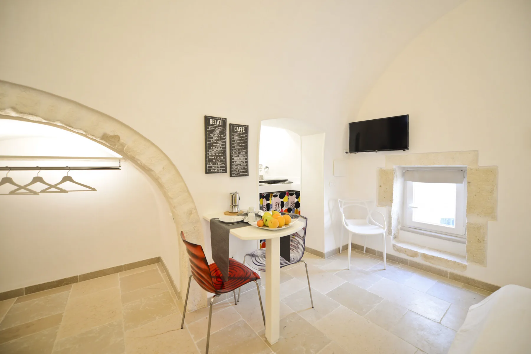 Una habitación luminosa con una mesa y asientos junto a una ventana enmarcada en piedra.