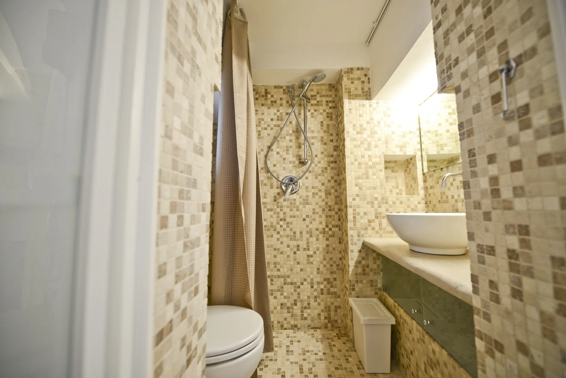 Un baño alicatado con ducha, inodoro y lavabo.
