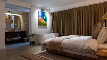 The Nepali Suite with a bed, bathtub and washroom area.