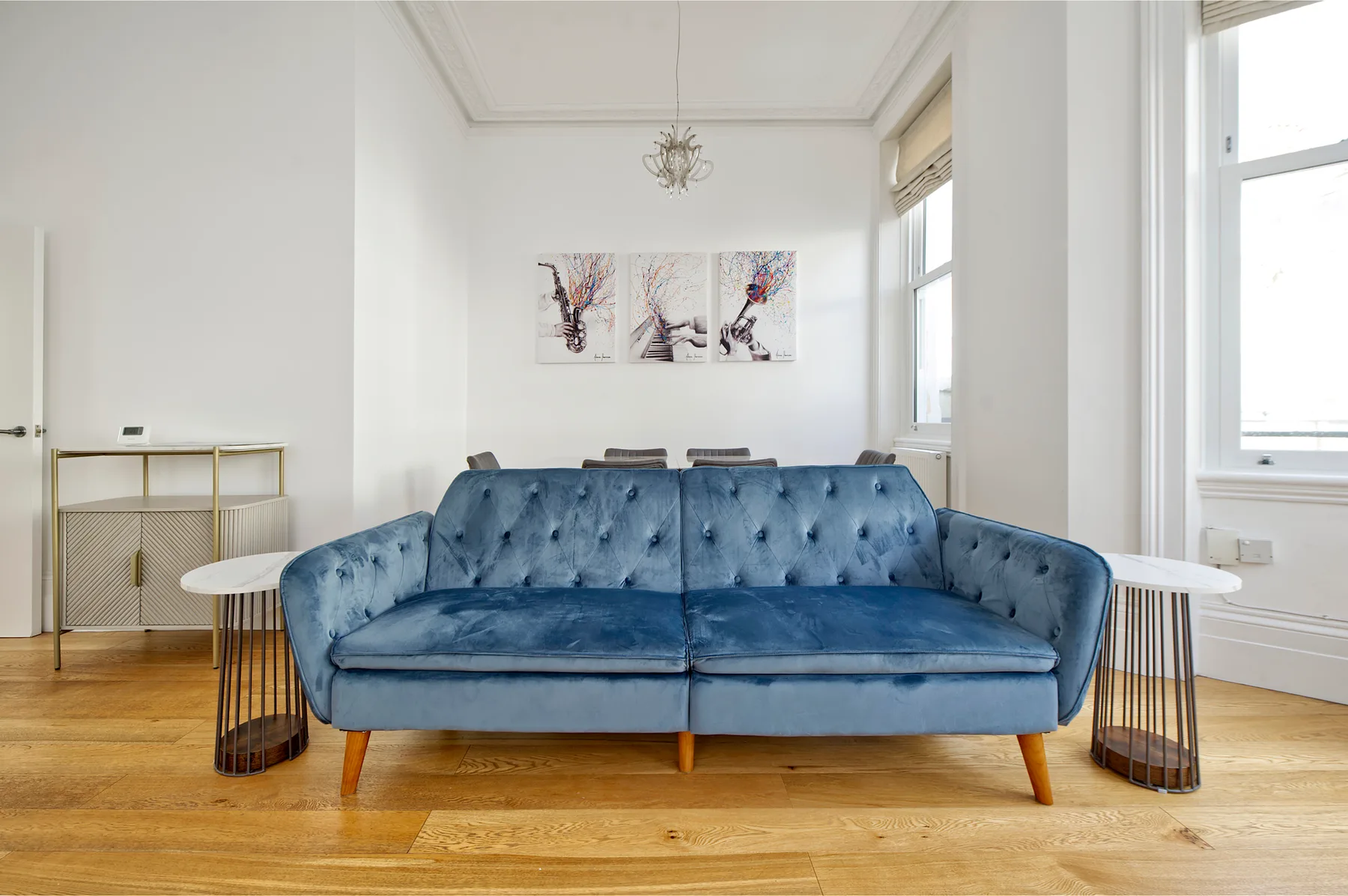 A bright living room with a blue sofa and artwork on the wall.