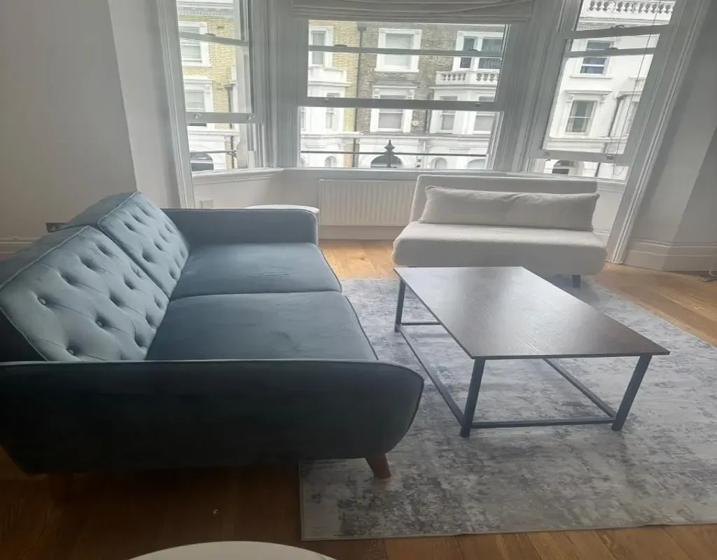 A living room with seating and a coffee table beside large windows.