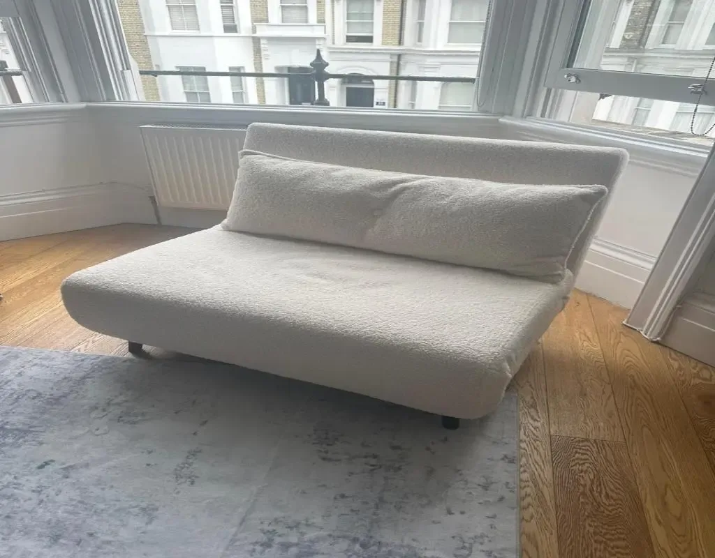 A bright sitting area with a light-colored sofa beside large windows.