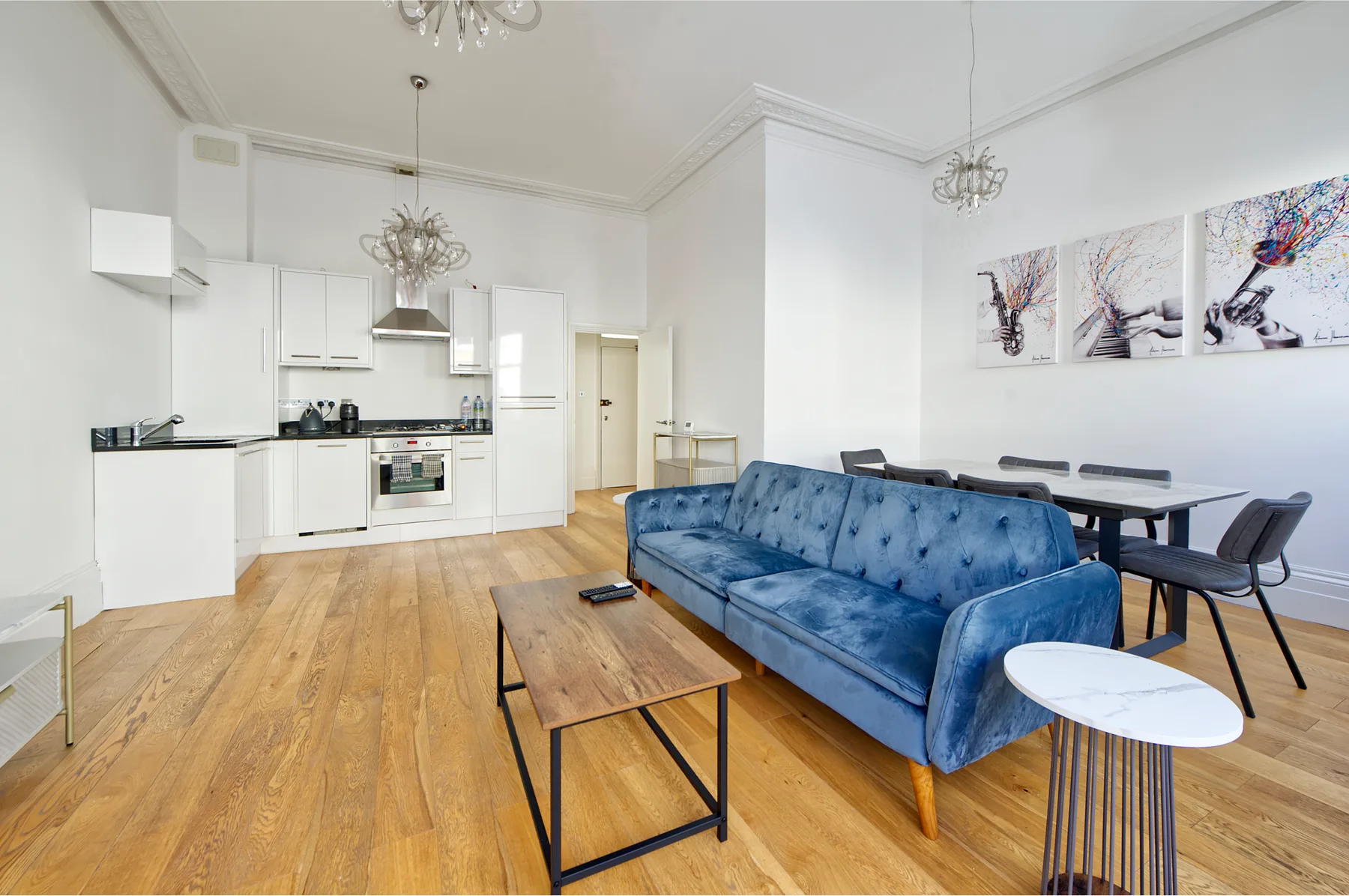 A bright open-plan living and dining area with a blue sofa and kitchen.
