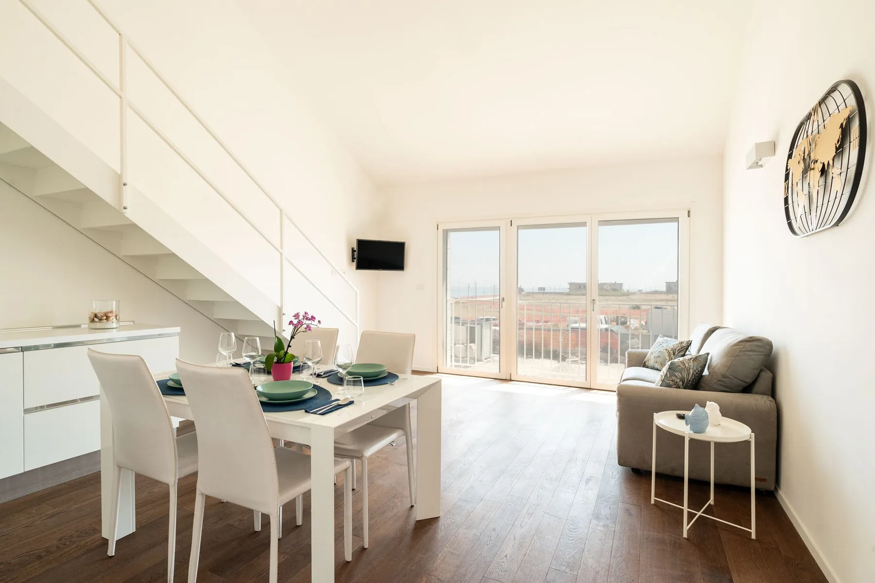 Una luminosa sala de estar y comedor de planta abierta, con grandes ventanales y una pequeña zona de descanso.