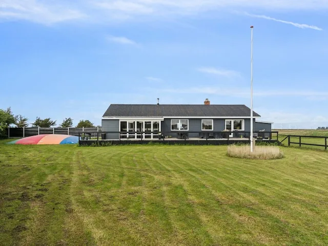 A long, single-story house stands beyond a wide grassy lawn.