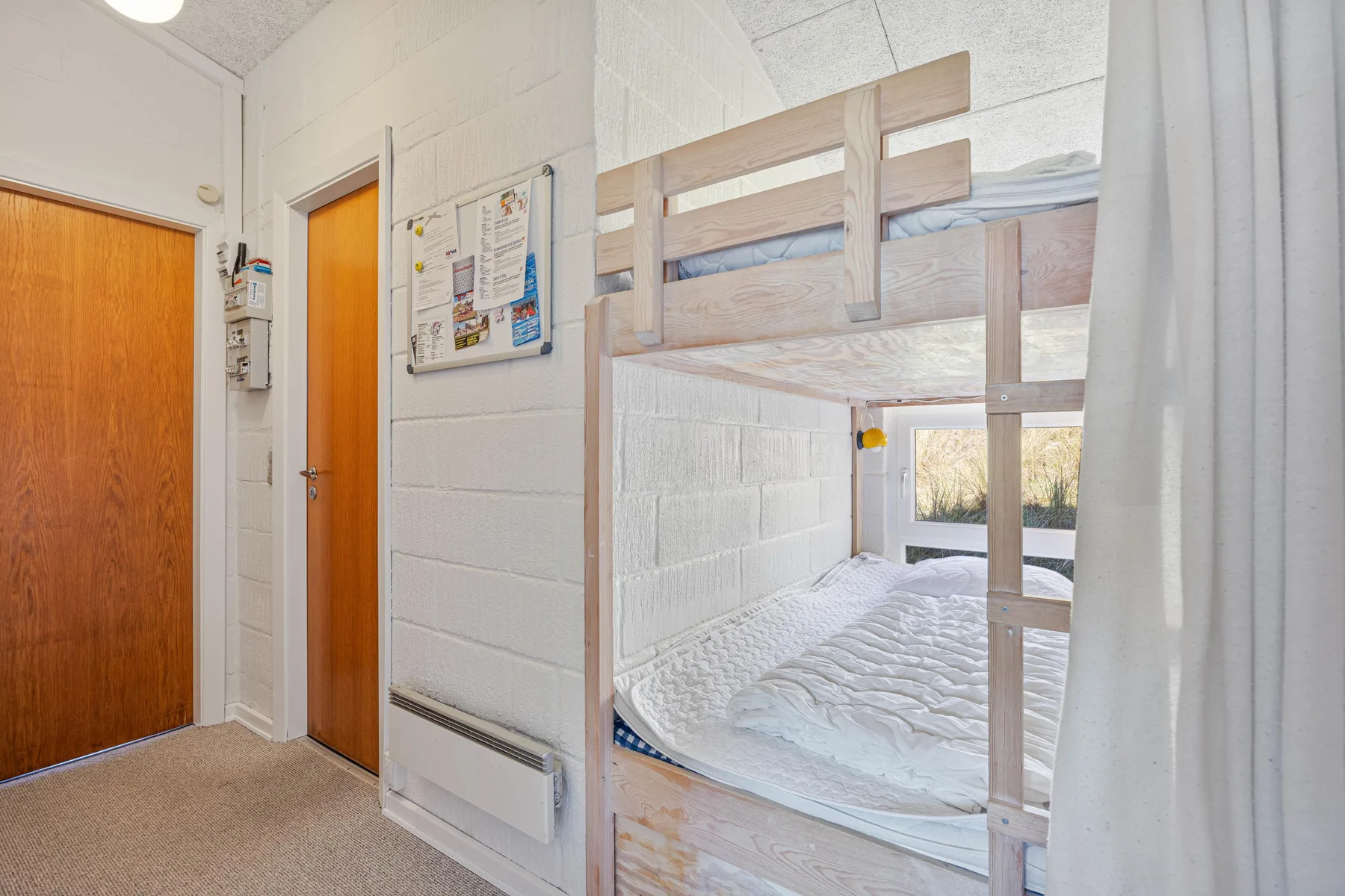 Un dormitorio con literas, ropa de cama blanca y puertas de madera.