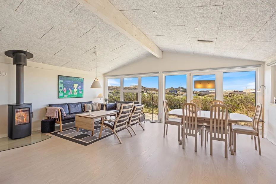 Una luminosa sala de estar y comedor de planta abierta con grandes ventanas hacia el paisaje.