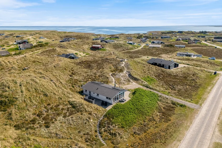Vista aérea de casas dispersas entre dunas arenosas cerca de la costa.