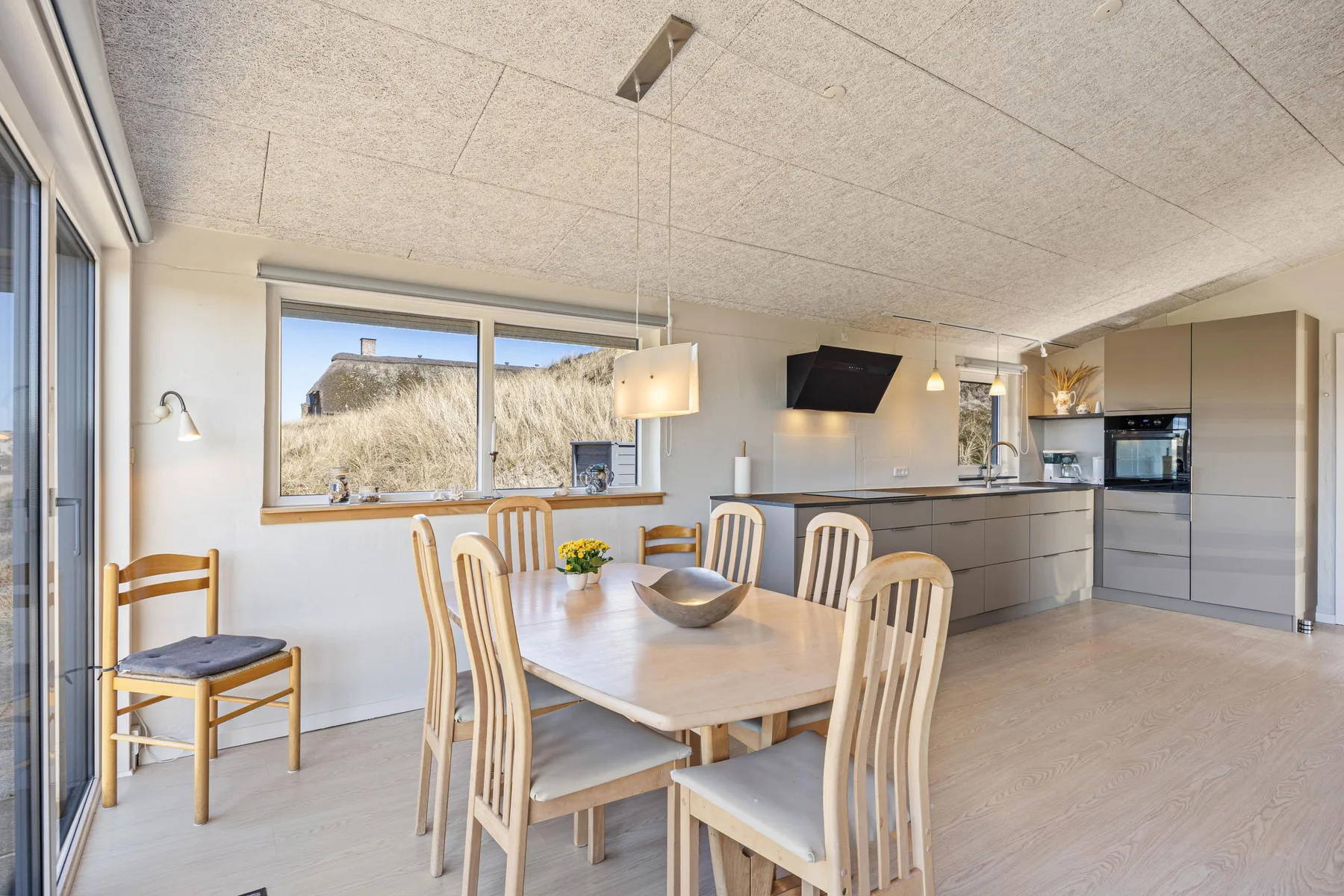 Un comedor luminoso con una mesa de madera junto a una cocina abierta.
