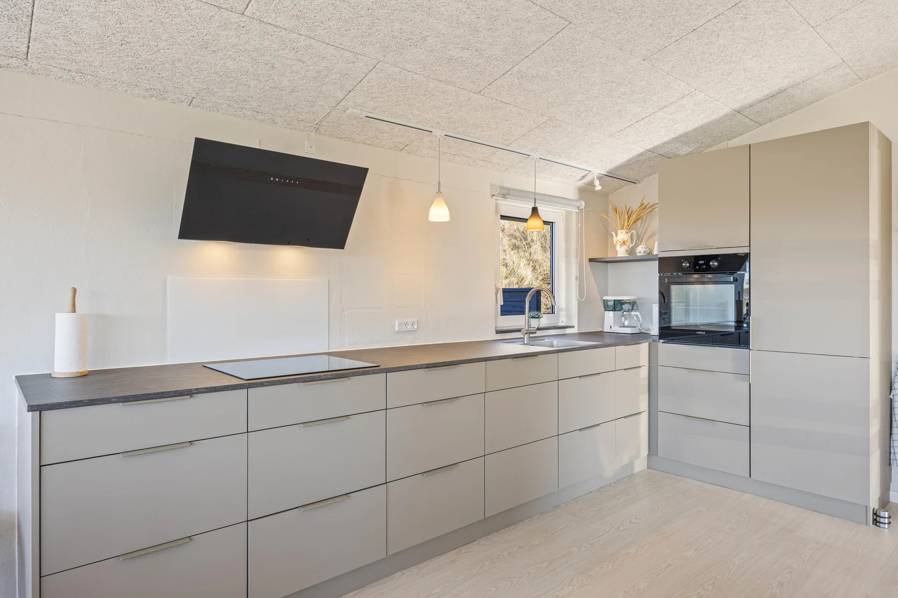 Una cocina moderna con gabinetes claros, una encimera oscura y electrodomésticos integrados.