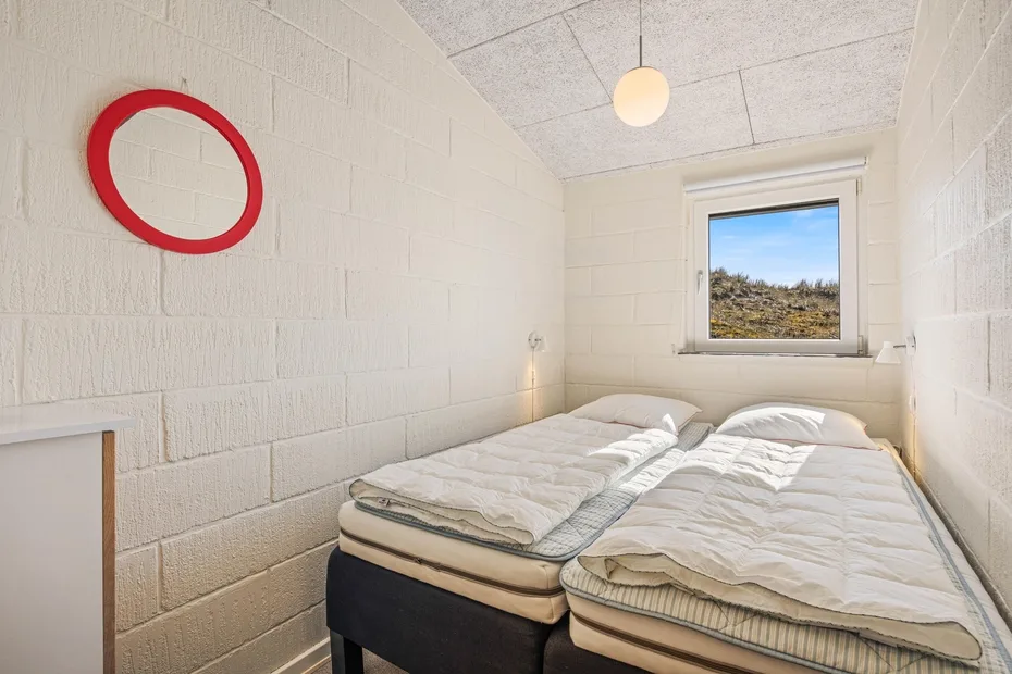 Un dormitorio con dos camas bajo una ventana.