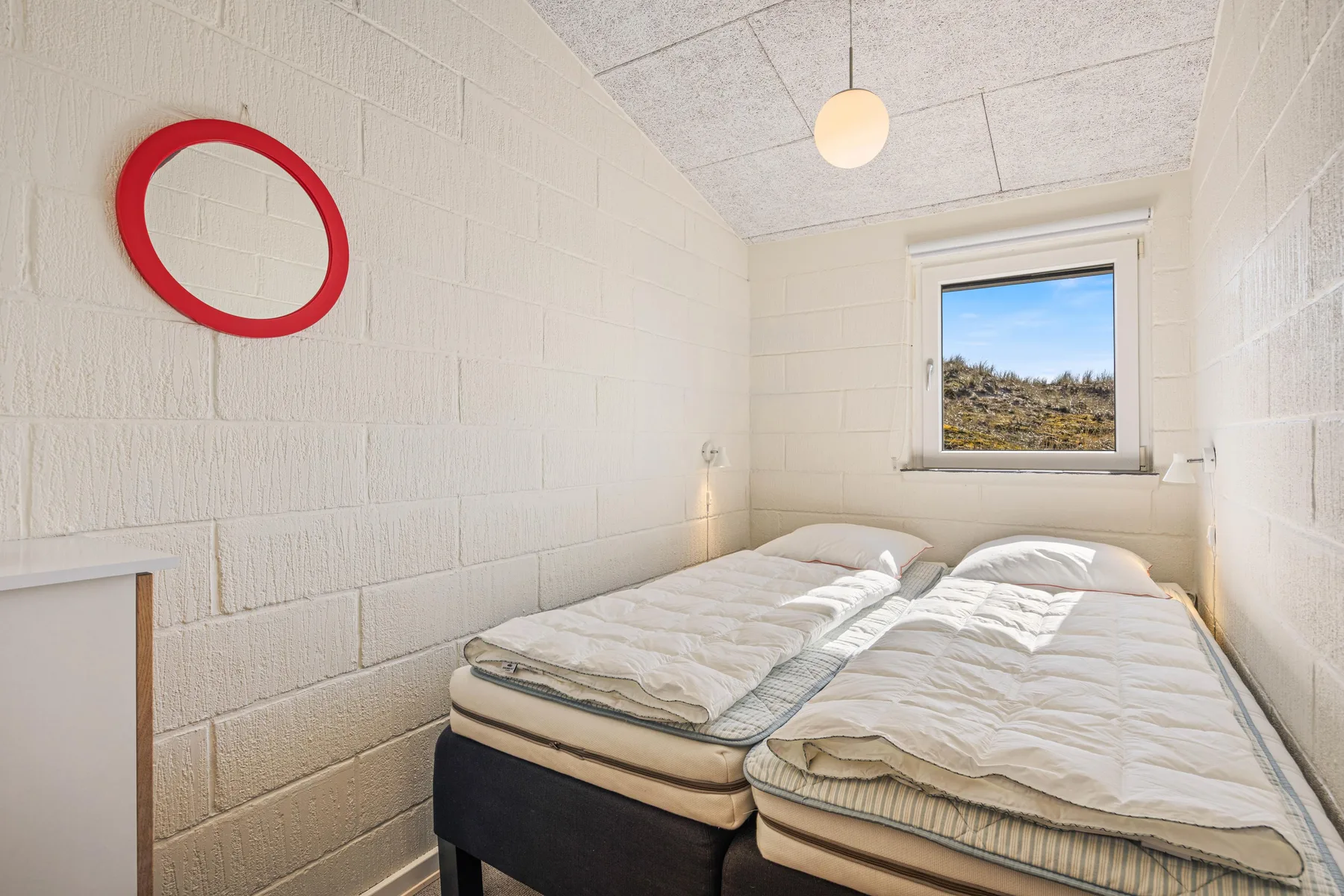 Dormitorio con dos camas bajo una ventana.