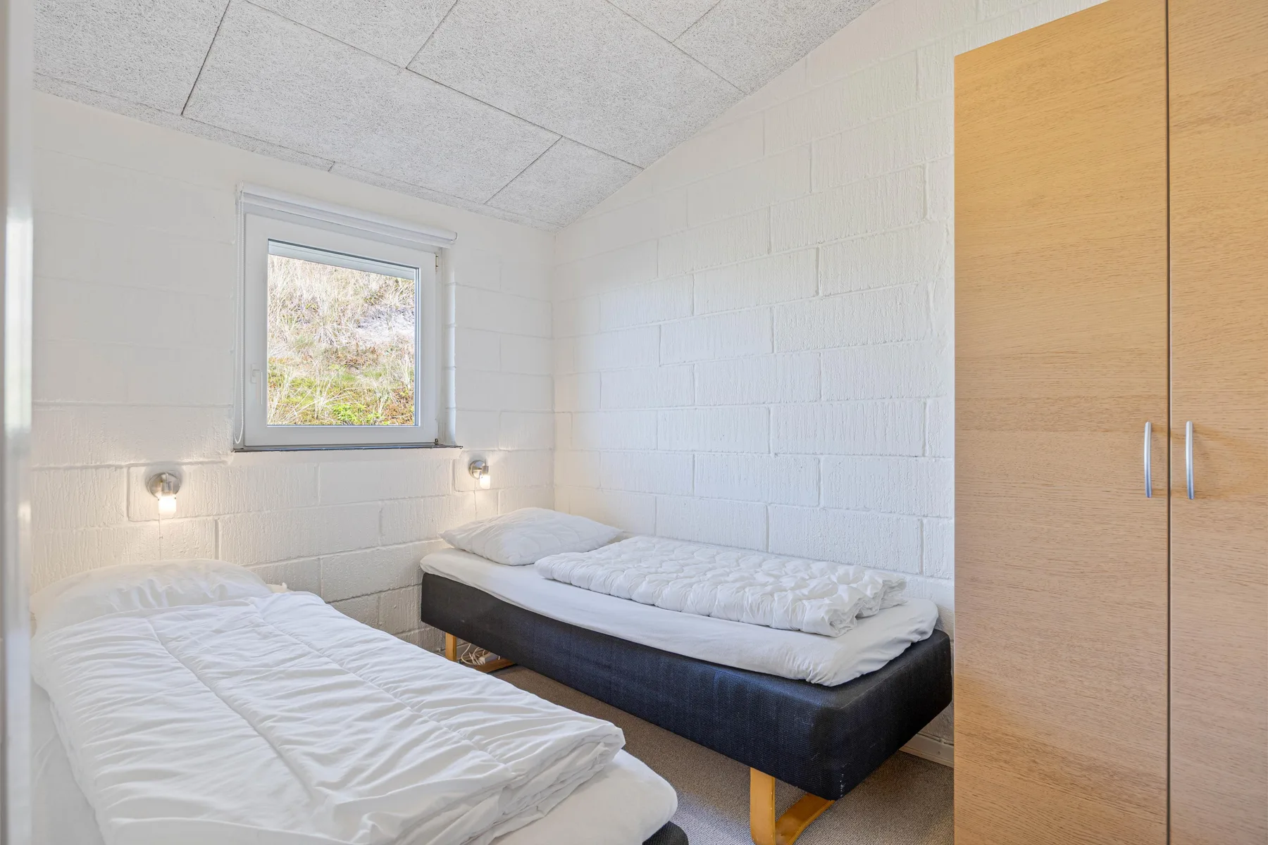 Un dormitorio luminoso con dos camas y una ventana.