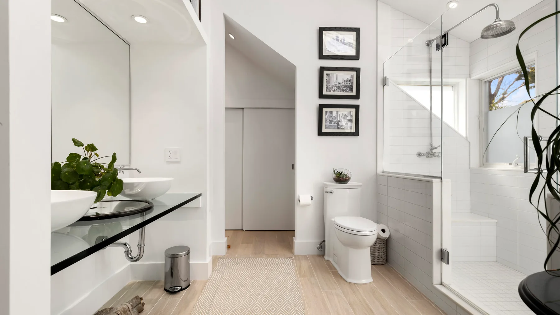 A bright bathroom with a toilet, vanity, and glass shower.