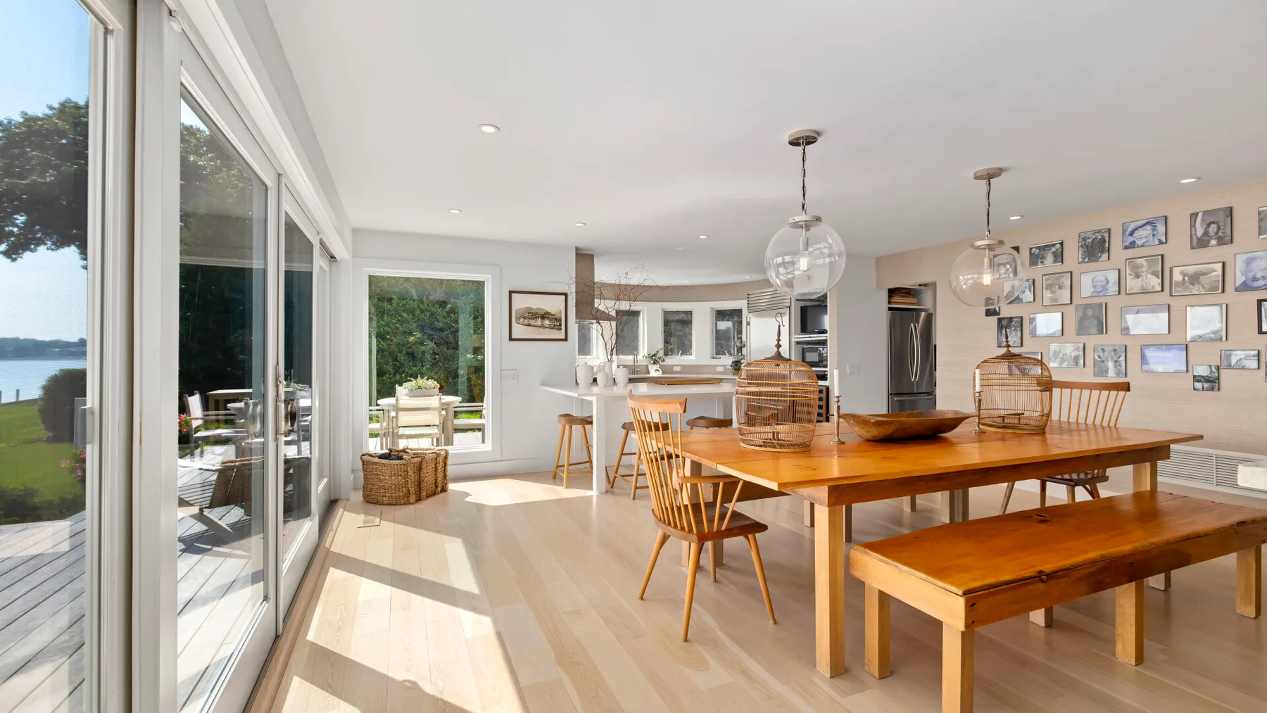 A bright dining area with a long wooden table beside large windows.