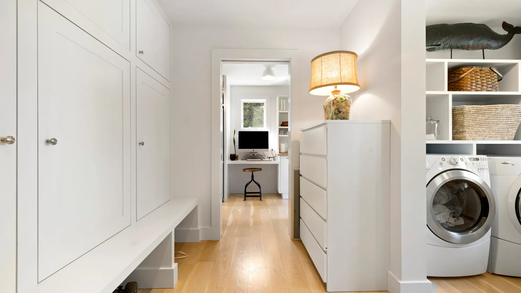 A bright hallway with built-in cabinets leads to a small workspace.