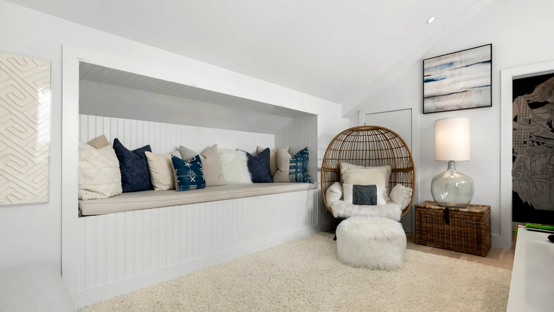 A bright bedroom with a built-in window seat and a cushioned hanging chair.
