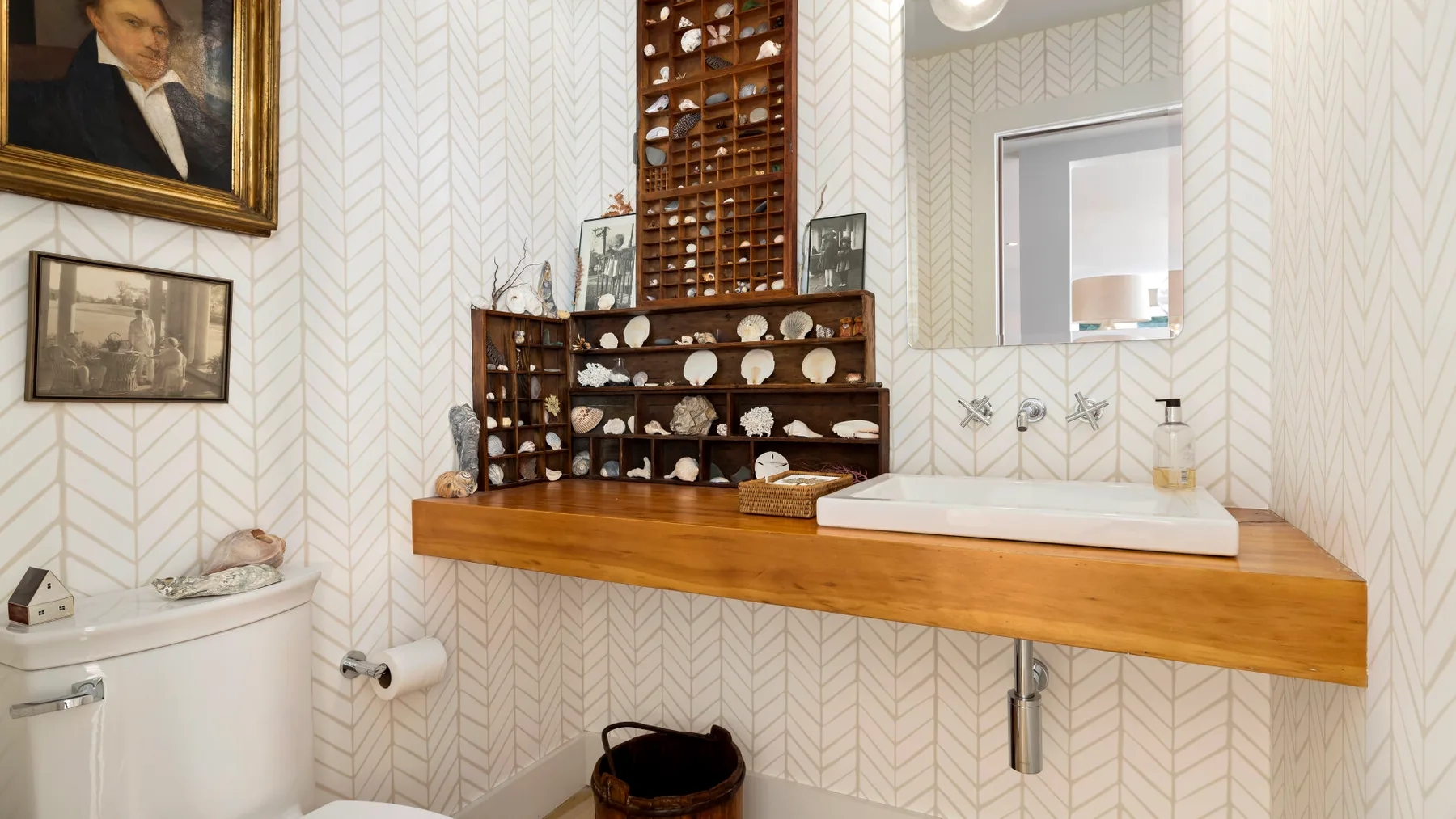A bathroom with a wide wooden vanity, vessel sink, and patterned walls.
