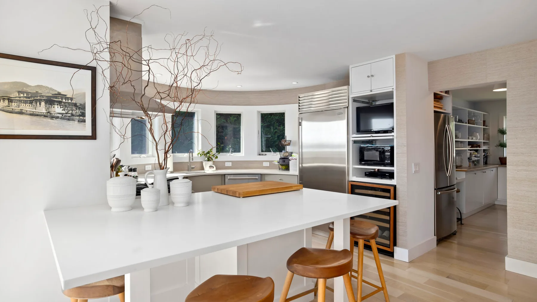 A bright modern kitchen with a large white island and stainless steel appliances.