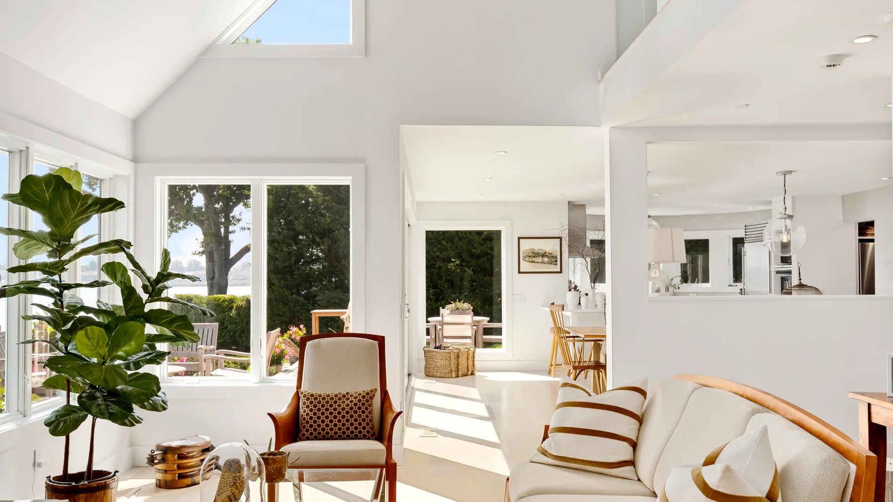 A bright open-plan living area with a sofa, an armchair, and large windows.