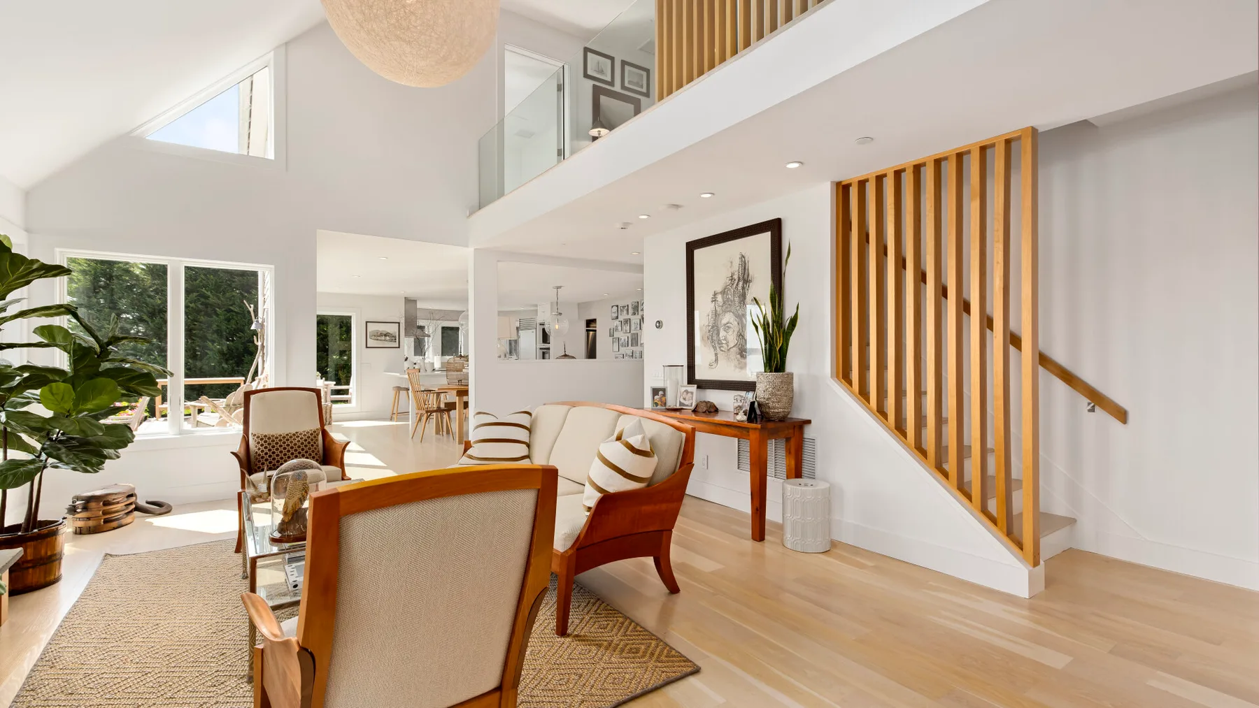 A bright open living area with seating beside a staircase and tall windows.
