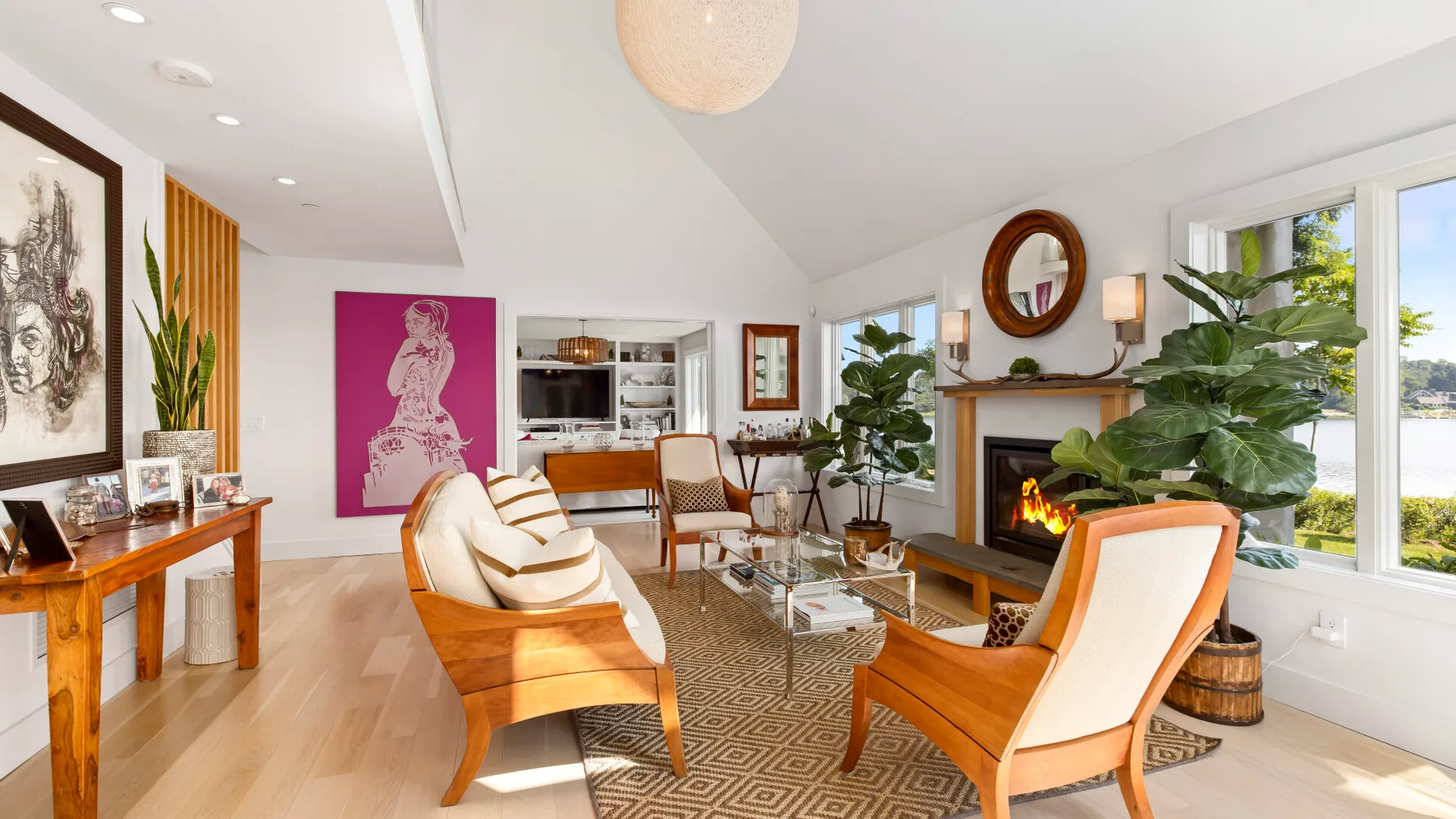 A bright living room with seating around a rug and a fireplace.