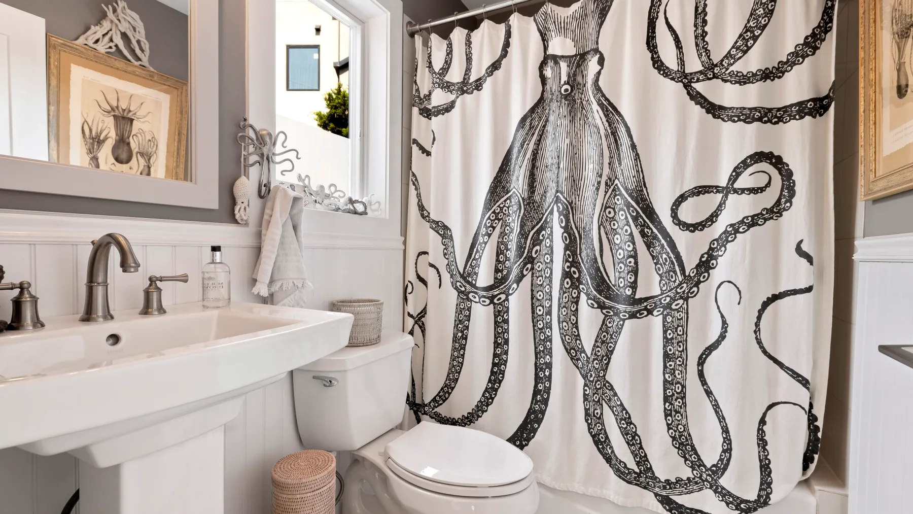 A bathroom with a white sink and an octopus-patterned shower curtain.