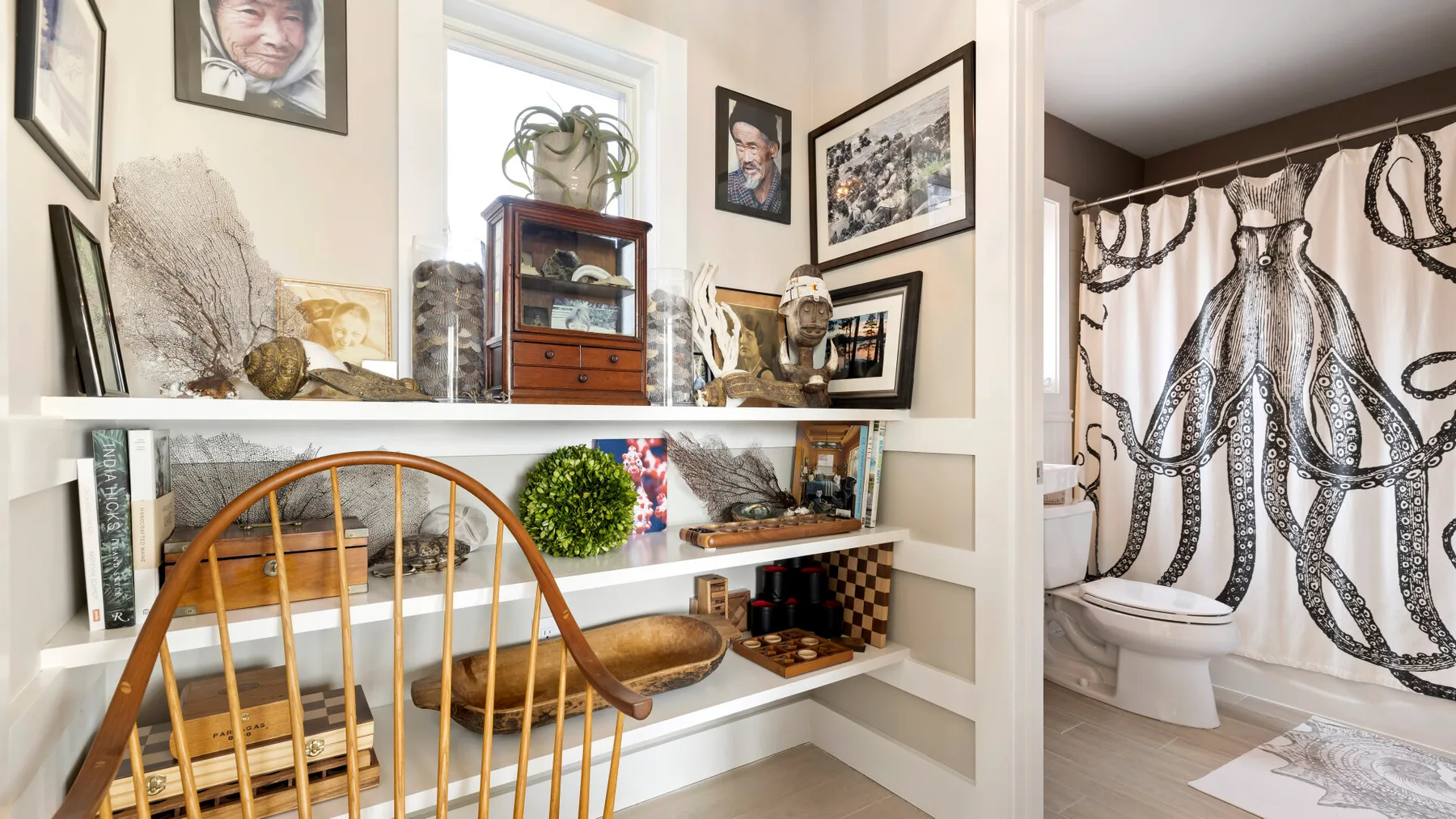 A room with built-in shelves displaying artwork and decorative objects beside a bathroom.