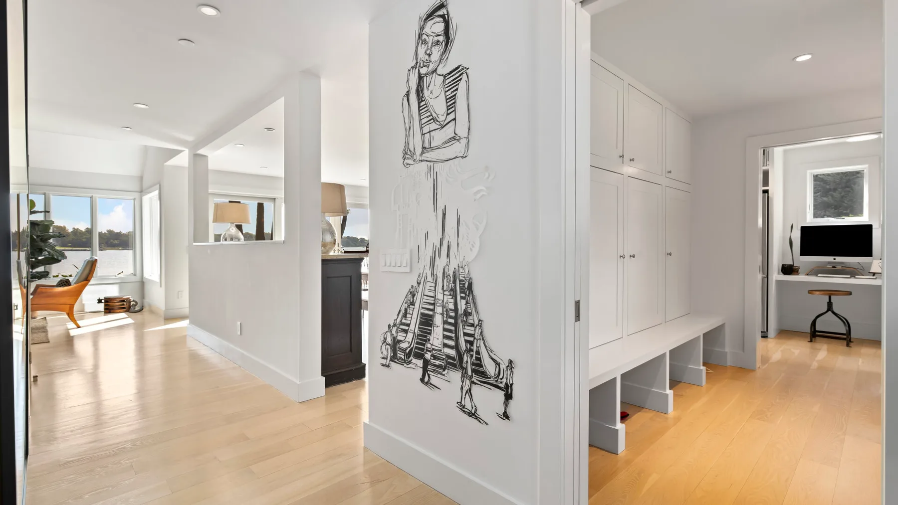 A bright interior hallway opens onto a living area, with a large black-and-white wall drawing.