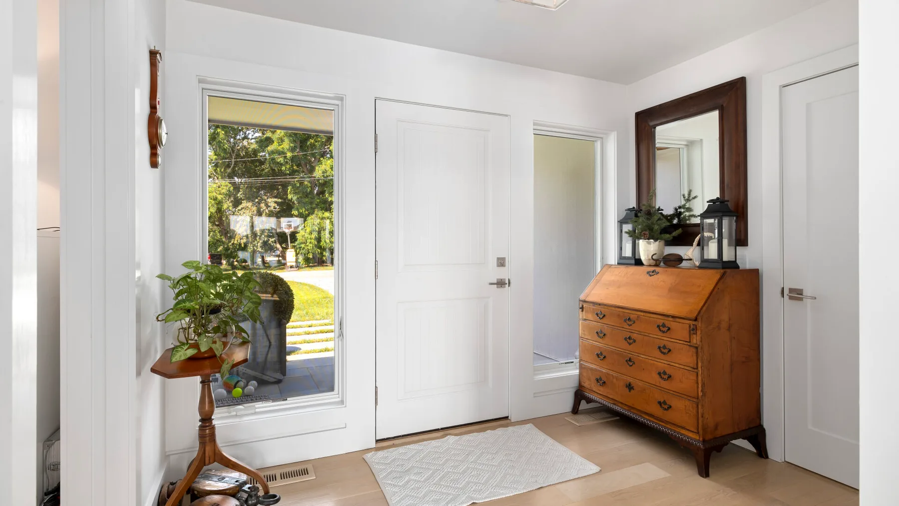 A bright room with a wooden dresser and a window overlooking greenery.