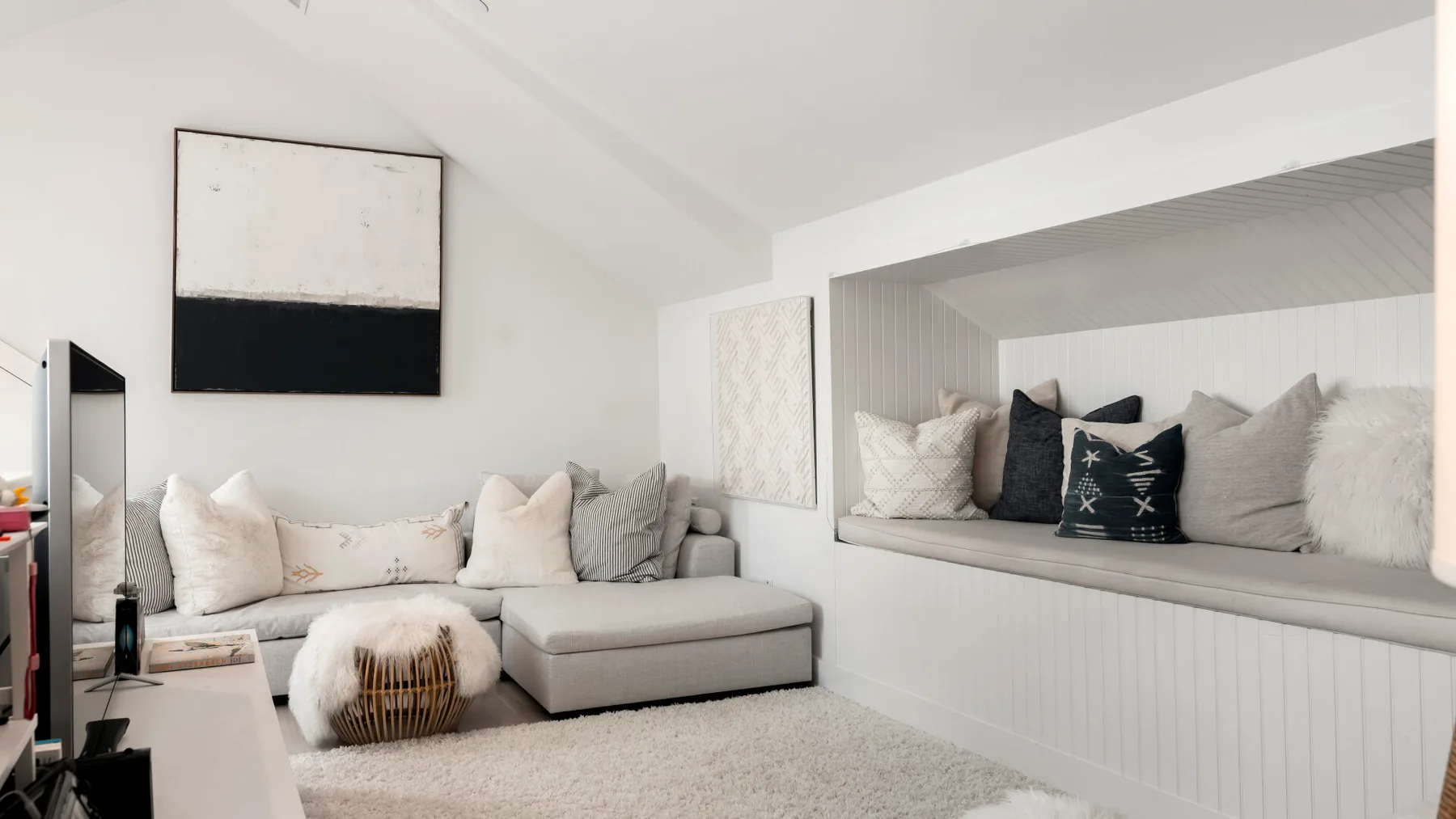 A bright living room with a sectional seating area and cushions in a wall niche.