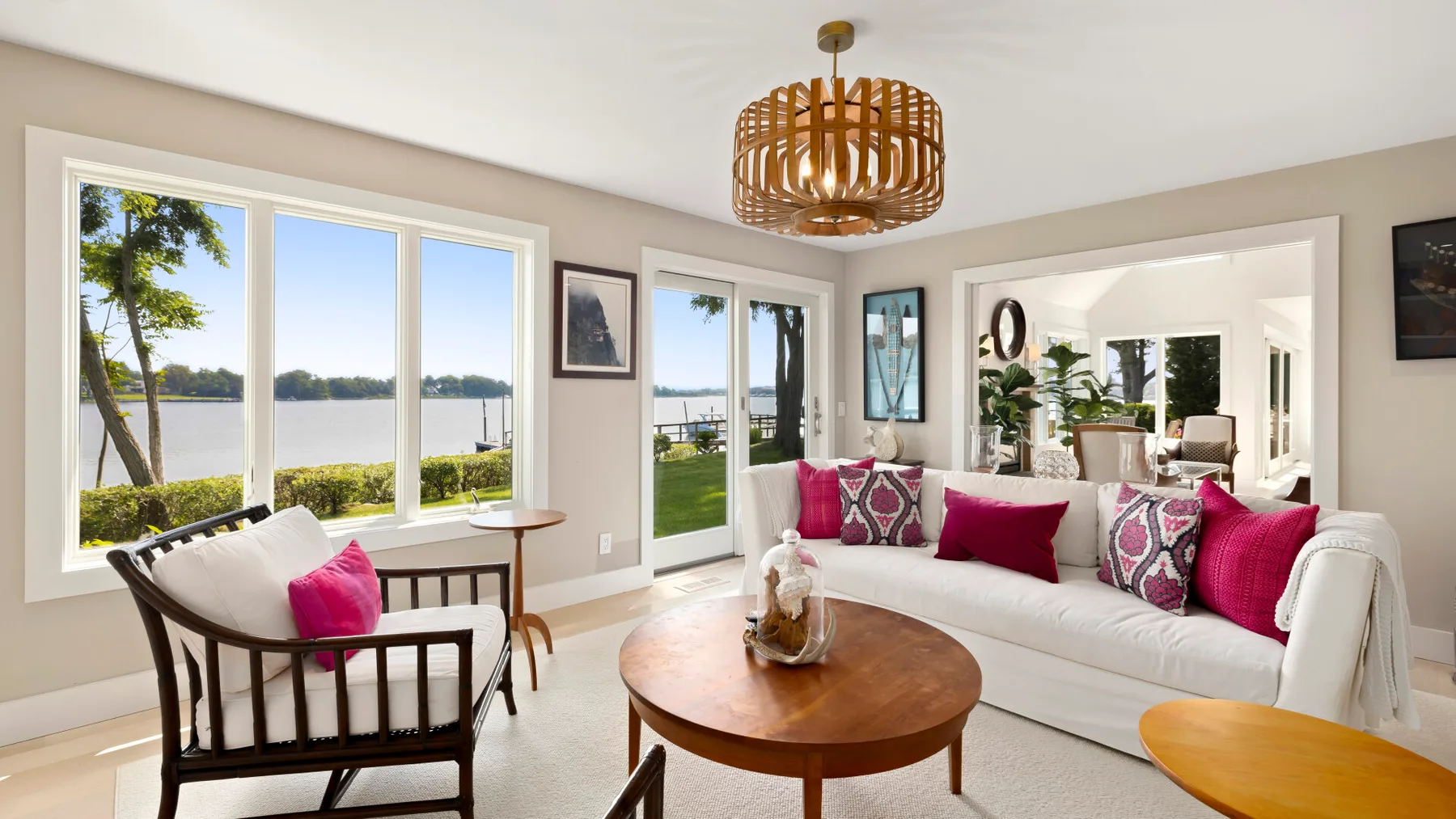 A bright living room with white seating, a wooden coffee table, and large windows.
