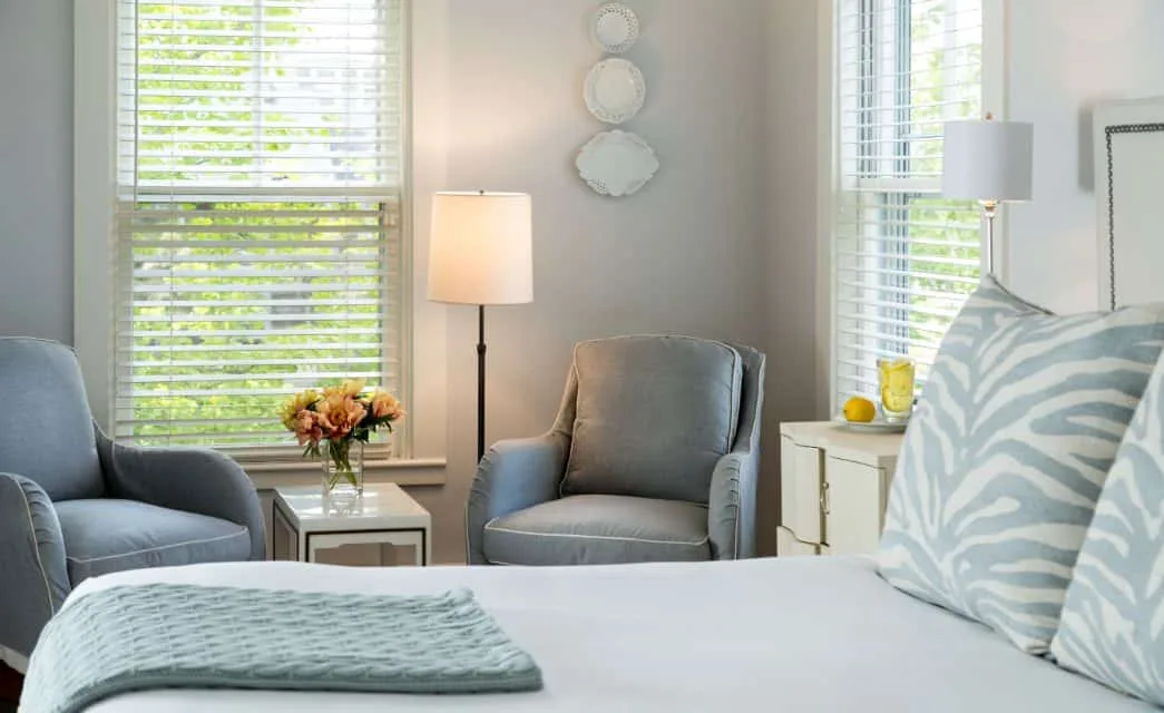 Habitación con ropa de cama azul claro, muebles de dormitorio blancos y sillas tapizadas en azul