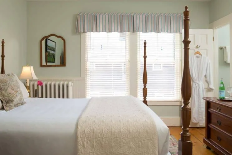 Dormitorio Empire con cama de cuatro postes de madera oscura y ventanas grandes