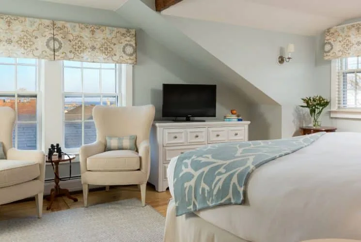 Dormitorio Brant Point con ropa de cama blanca y zona de estar con sillas de color crema