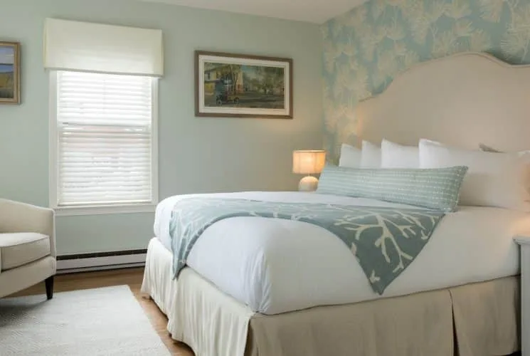 Dormitorio Campanula con ropa de cama blanca y sillas tapizadas en color crema