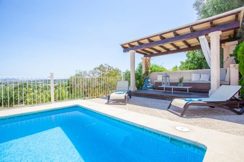 Una piscina junto a una zona de estar exterior cubierta con vistas a la vegetación.