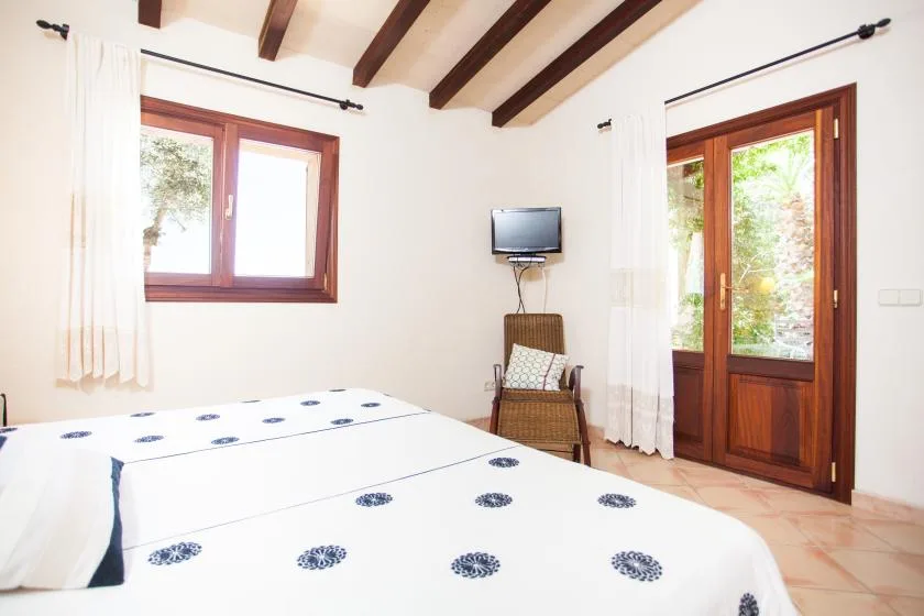 Un dormitorio luminoso con ropa de cama estampada, una ventana y una puerta acristalada.