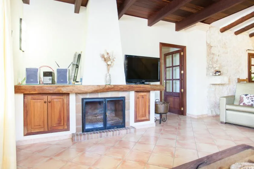 Una sala luminosa con chimenea, televisor y suelo de baldosas claras.