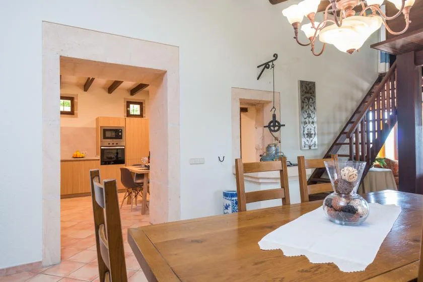 Un comedor con una mesa de madera y la cocina visible a través de la puerta.